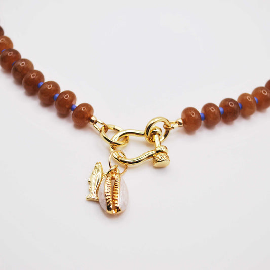 'golden dune' beaded necklace with horse shoe carabiner and cowrie shell and fish charm