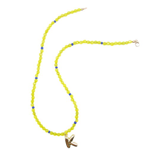 Inspired by shimmering water under shifting tides, the 'tidal glow' necklace features handcrafted bold neon beads with a gold initial charm. 